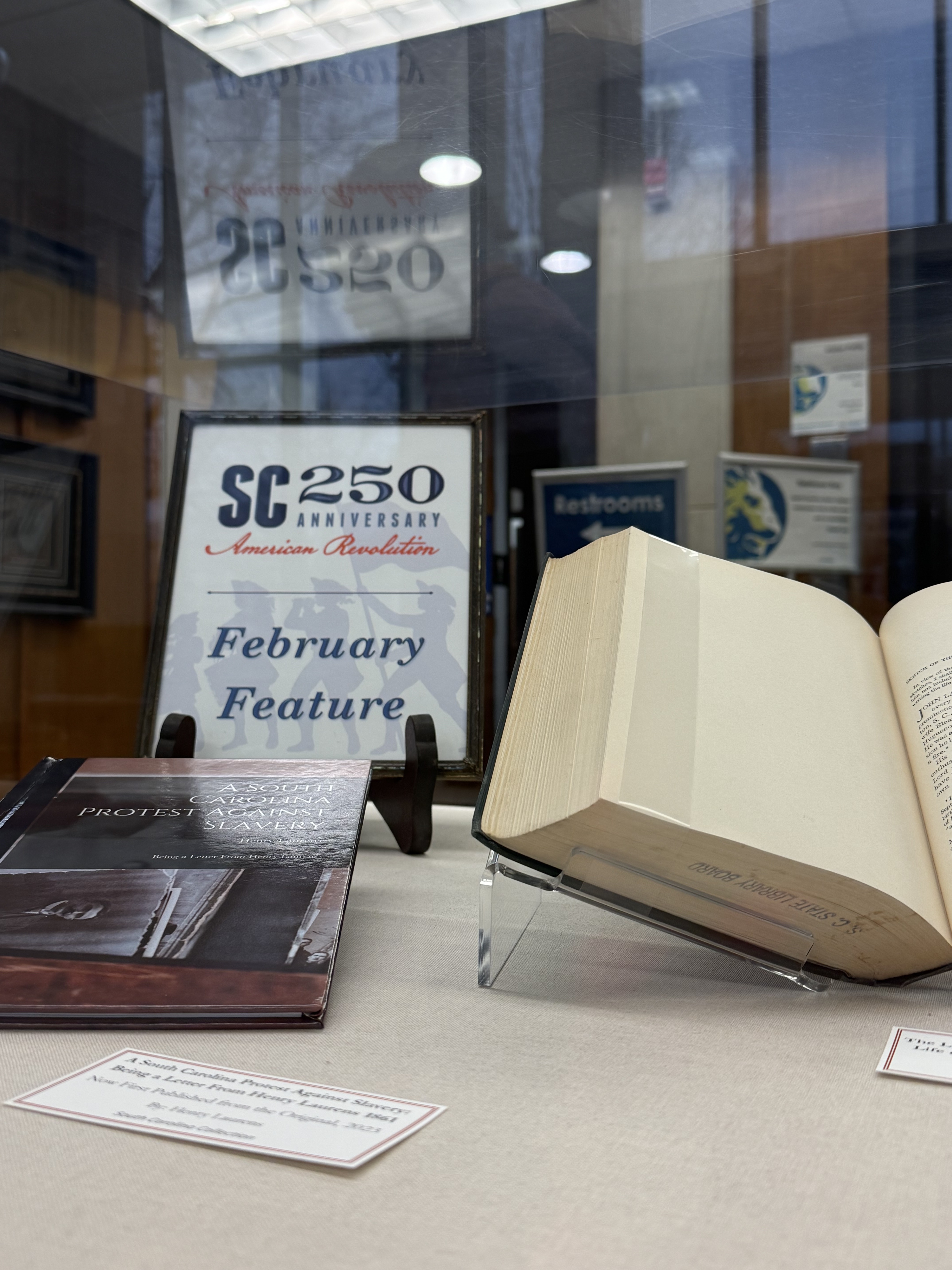 Open book and the SC250 Logo on a sign that reads February Feature.