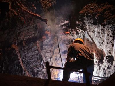 Miner backlit in a mine.
