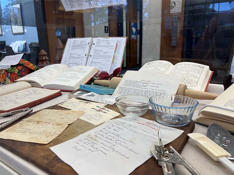 A selection of typewritten ansd hand written recipes are in our glass display case with some kitchen utensils and Christmas ribbons