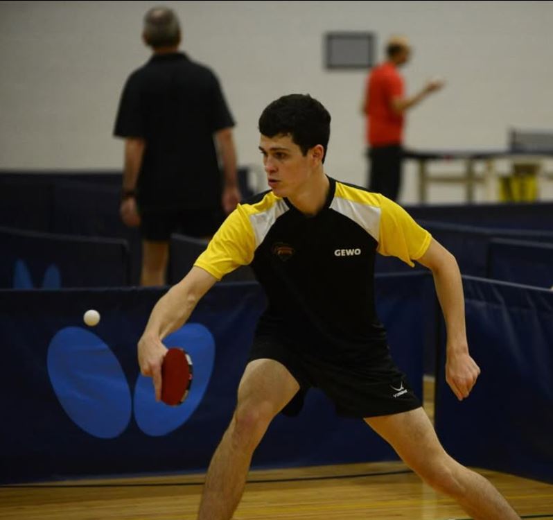 Tripp Roche about to hit a ping pong ball in a match.