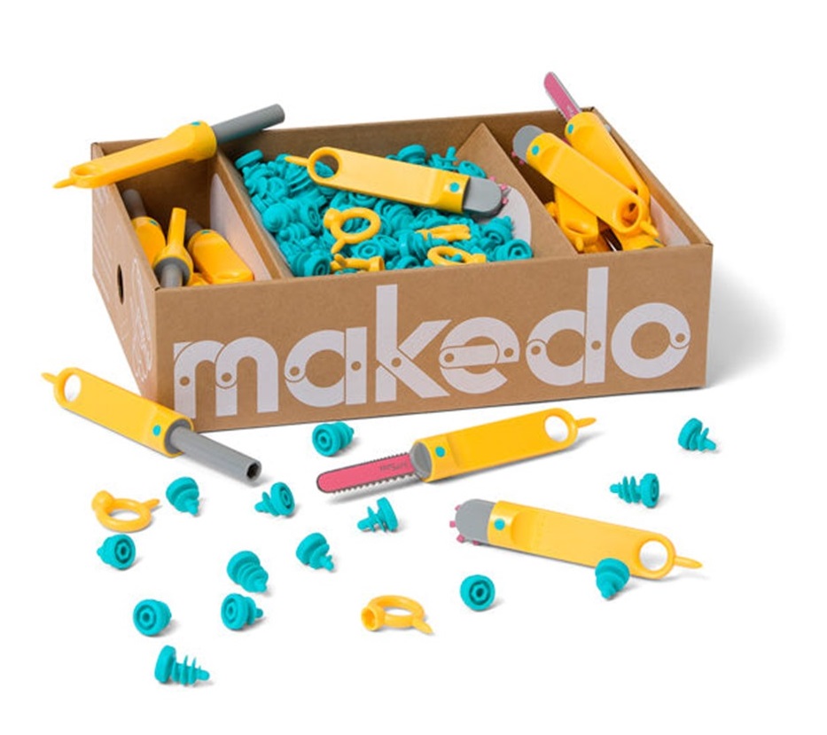 The Makedo kit open box with plastic screws and tools lying around.