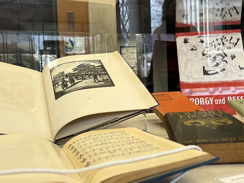 Selected open books in the State Library's display case from the A.S. Salley Collection in the display case, with a copy of Porgy & Bess propped upright on the right.