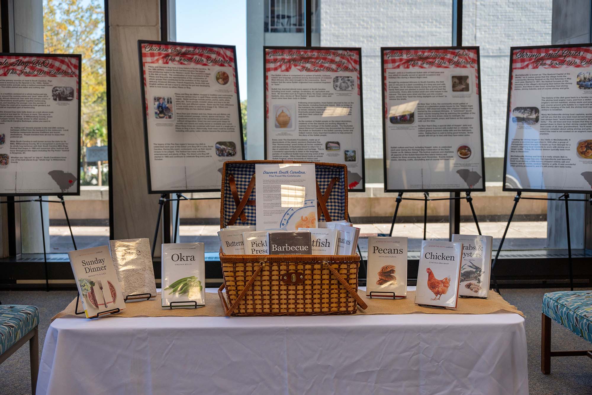 A display table in the State Library with a selection of books on different foods. In the background can be seen easels with posters describing South Carolina food traditions