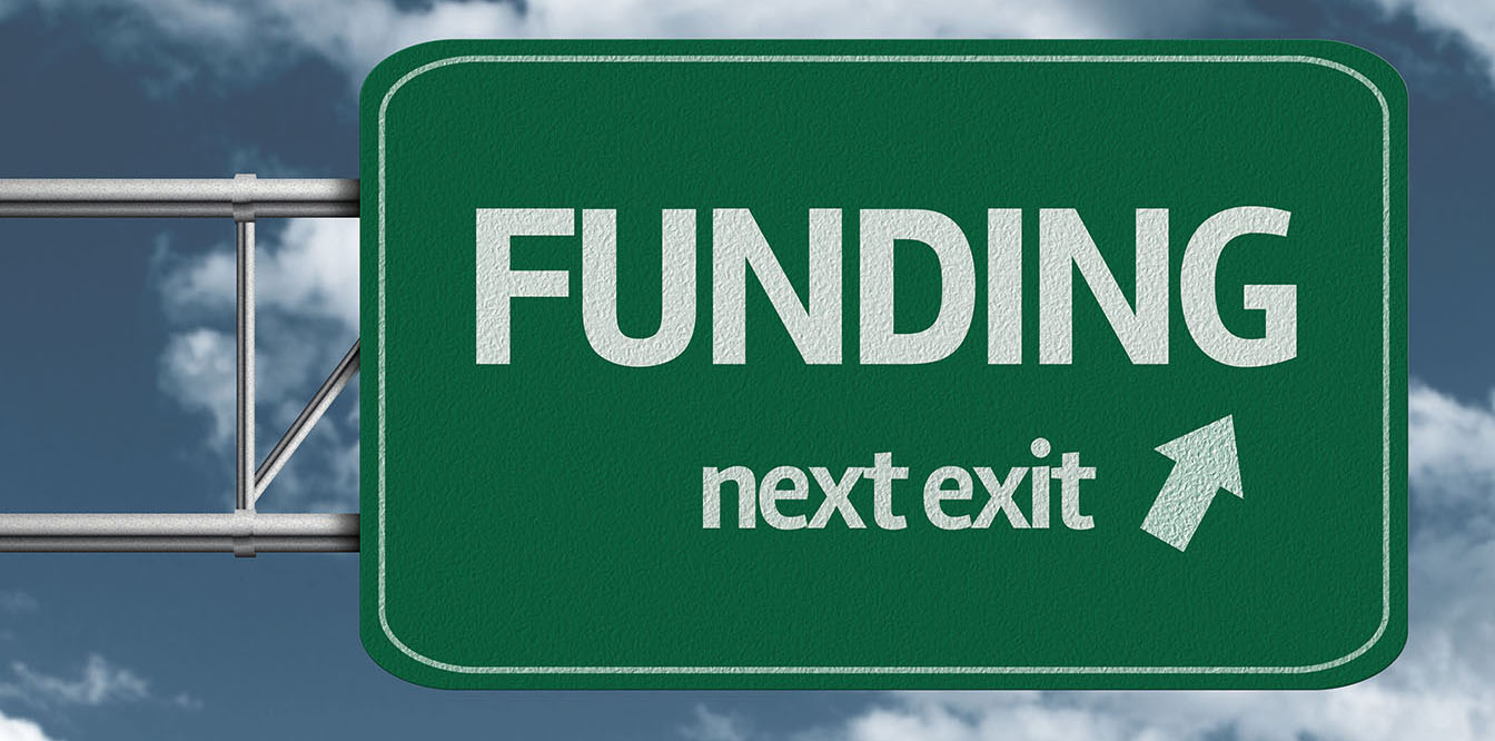 Highway sign that says "FUNDING next exit" with an arrow pointing to the exit