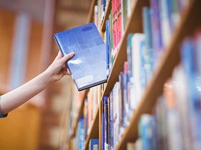 Hand grabbing a book off of a library shelf