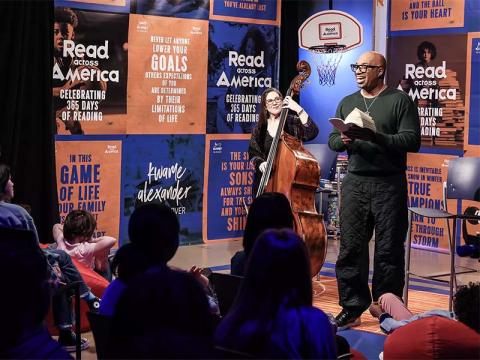 Kwame Alexander reads The Crossover to small audience of middle school students accompanied by a female cellist - courtesy of the NEA website