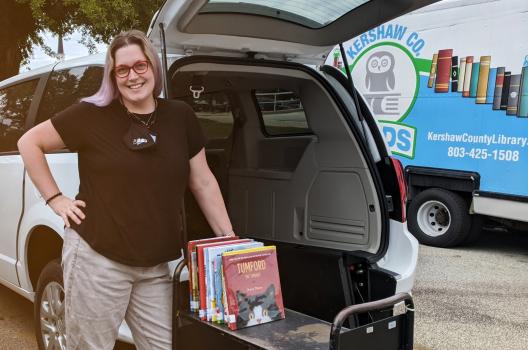A library staffer from Keshaw County Library standing beside the upgraded programming van.